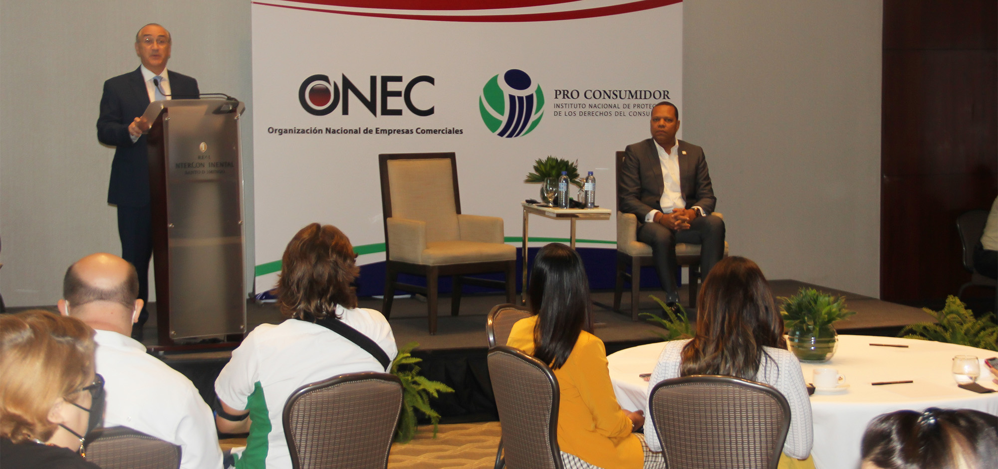 El presidente de la Organización Nacional de Empresas Comerciales (ONEC), Mario Lama Haché, habla en el encuentro. A su lado, el director ejecutivo de Pro Consumidor, doctor Eddy Alcántara.